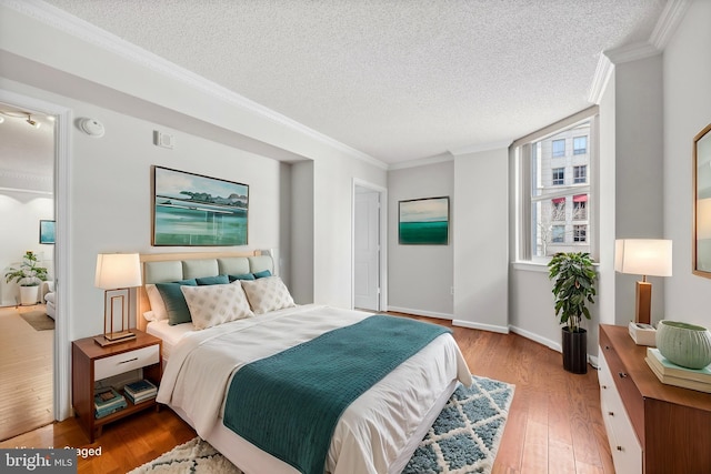 bedroom with ornamental molding, light hardwood / wood-style flooring, and a textured ceiling