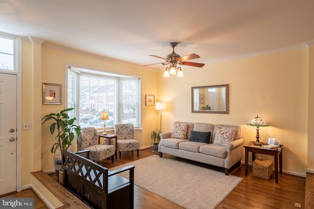 living room featuring wood-type flooring, ornamental molding, and ceiling fan