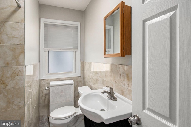 bathroom featuring vanity, toilet, and tile walls