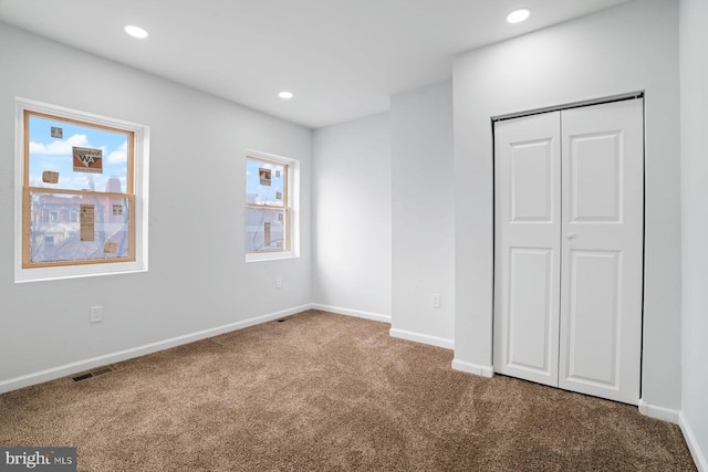 unfurnished bedroom with multiple windows, carpet floors, and a closet