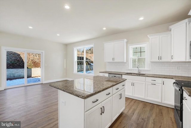 kitchen featuring sink, black range with electric cooktop, a kitchen island, dark stone counters, and white cabinets