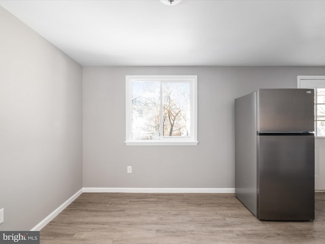 kitchen featuring stainless steel fridge, light wood-type flooring, and a wealth of natural light