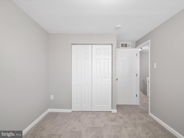 unfurnished bedroom with light colored carpet and a closet