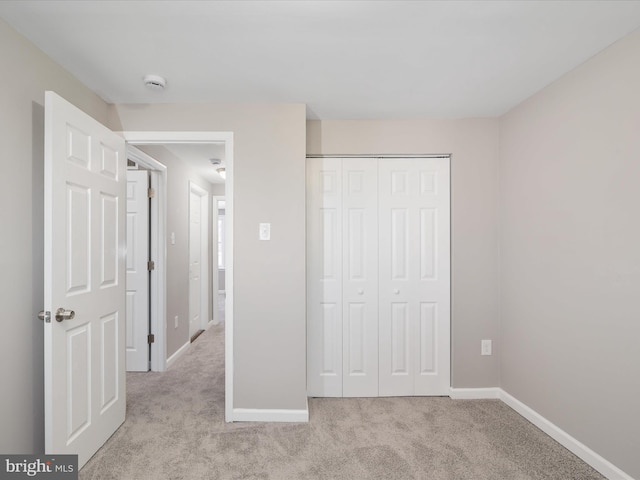 unfurnished bedroom with light colored carpet and a closet