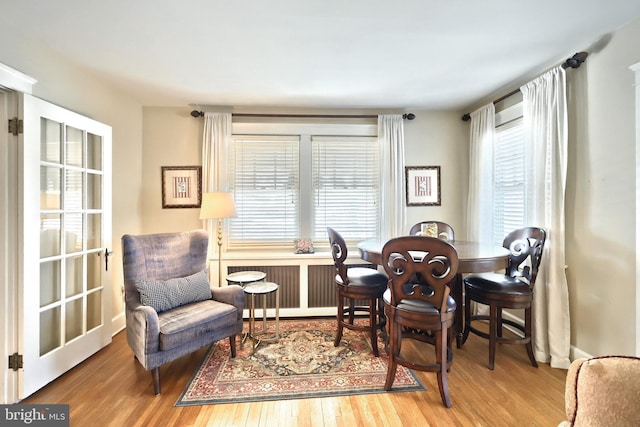 dining area with hardwood / wood-style flooring and radiator heating unit