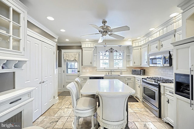 kitchen with sink, a breakfast bar area, white cabinetry, stainless steel appliances, and a kitchen island