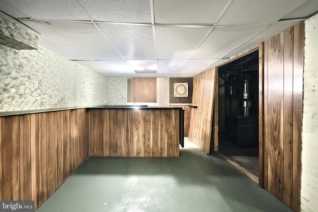 bar featuring a paneled ceiling, concrete floors, and wood walls