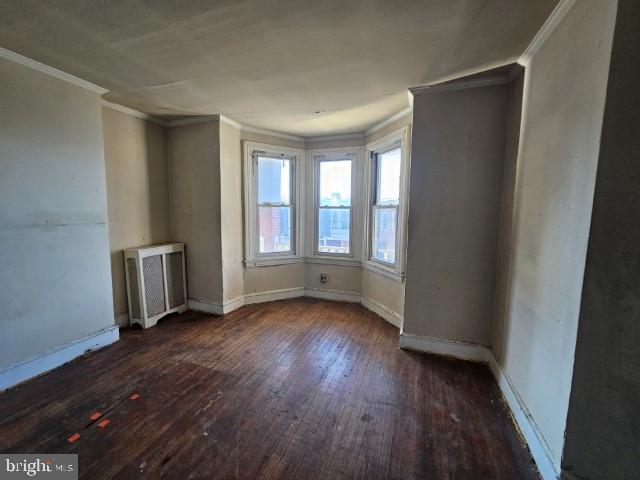 unfurnished room featuring dark wood-type flooring and ornamental molding