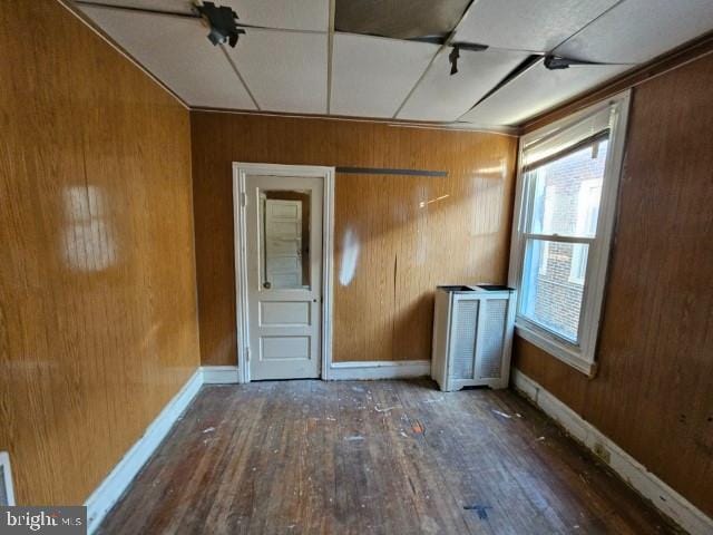 empty room with dark wood-type flooring and wood walls