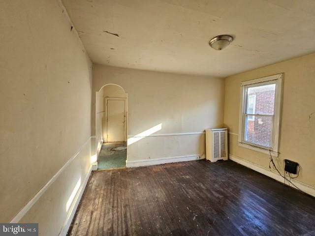 empty room featuring radiator heating unit and dark hardwood / wood-style floors