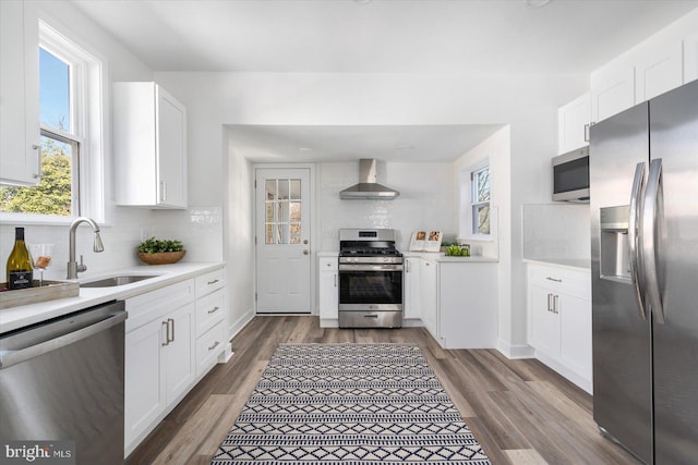 kitchen featuring white cabinetry, appliances with stainless steel finishes, sink, and wall chimney exhaust hood