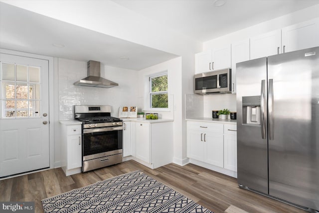 kitchen with tasteful backsplash, white cabinets, stainless steel appliances, and wall chimney range hood