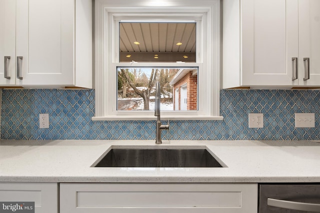 kitchen featuring white cabinetry, sink, and light stone counters