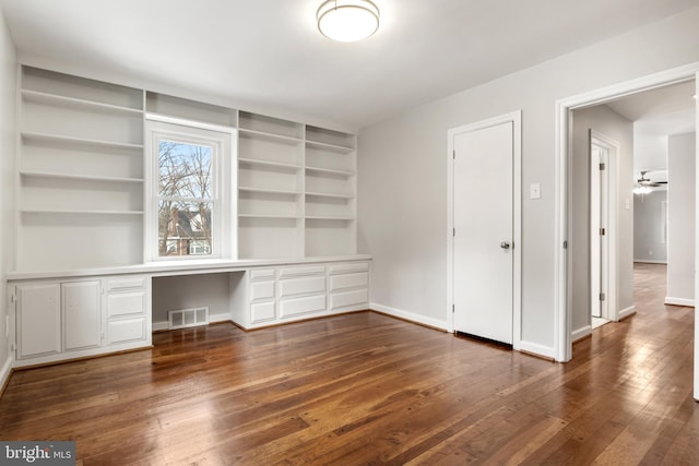 unfurnished office featuring dark wood-type flooring and built in desk