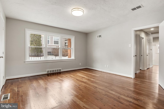 empty room with hardwood / wood-style floors and a textured ceiling