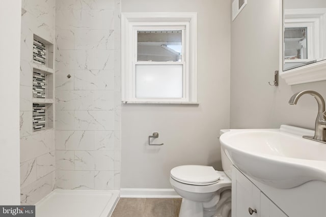 bathroom featuring vanity, toilet, and tiled shower