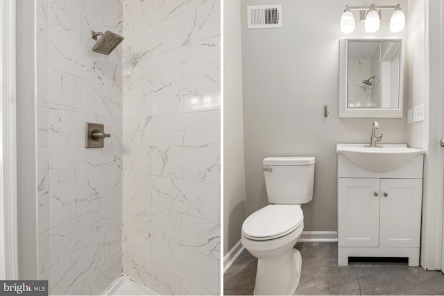 bathroom featuring vanity, tiled shower, and toilet