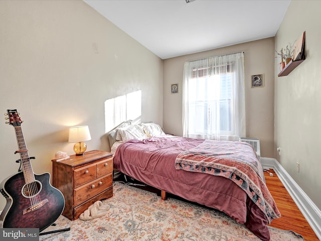 bedroom with a wall unit AC and light hardwood / wood-style flooring