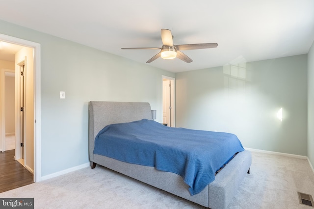 carpeted bedroom with a ceiling fan, visible vents, and baseboards