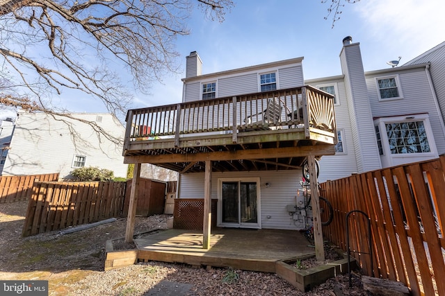 back of property featuring a wooden deck, a fenced backyard, and a chimney