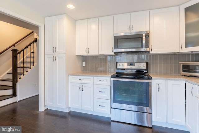 kitchen with decorative backsplash, white cabinets, appliances with stainless steel finishes, and dark wood-style flooring