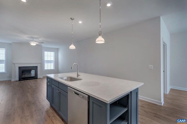 kitchen with sink, wood-type flooring, hanging light fixtures, dishwasher, and an island with sink