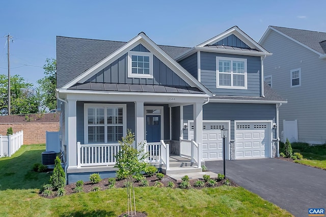 view of front of house featuring cooling unit, a garage, a front yard, and covered porch