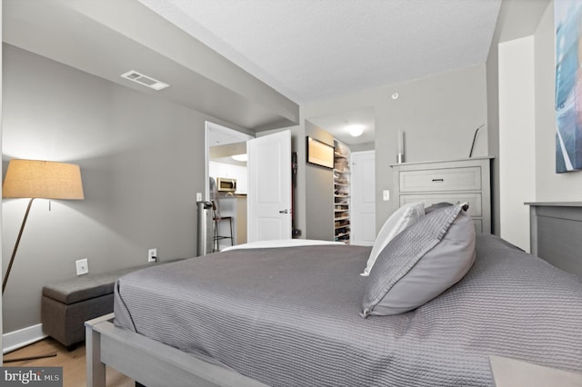 bedroom featuring a spacious closet, a textured ceiling, and hardwood / wood-style flooring