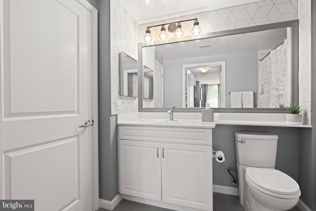 bathroom with tile patterned floors, vanity, toilet, and curtained shower