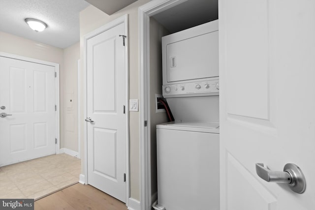 laundry room featuring stacked washer / dryer and a textured ceiling