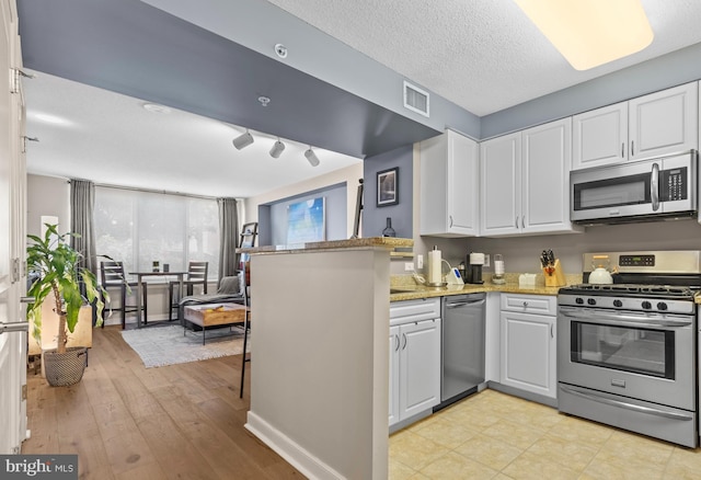 kitchen featuring stainless steel appliances, white cabinetry, and kitchen peninsula