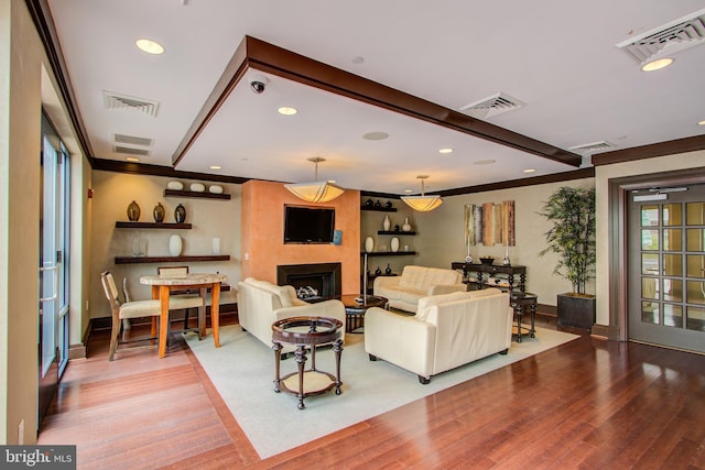 living room featuring hardwood / wood-style flooring, ornamental molding, a fireplace, and beam ceiling