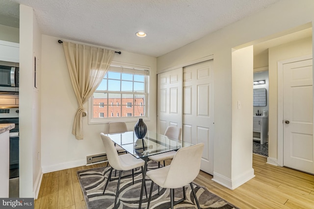 dining area featuring light hardwood / wood-style floors and a textured ceiling