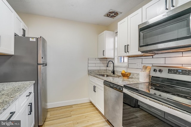 kitchen featuring light stone countertops, white cabinetry, appliances with stainless steel finishes, and sink