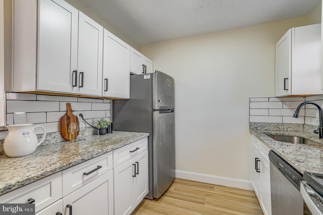 kitchen with sink, light stone countertops, white cabinets, and appliances with stainless steel finishes