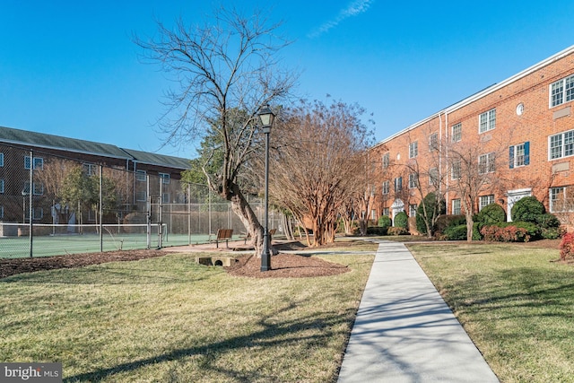 view of home's community with a lawn and tennis court