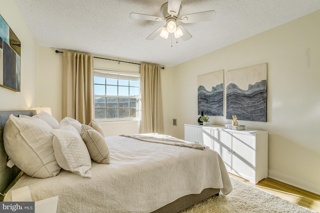 bedroom featuring ceiling fan, light hardwood / wood-style flooring, and a textured ceiling