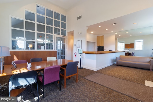 carpeted dining space with a high ceiling