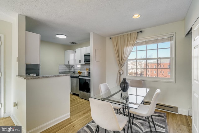 dining area with sink, a textured ceiling, and light hardwood / wood-style floors