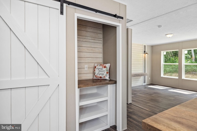 interior space with wood-type flooring, a barn door, and a textured ceiling