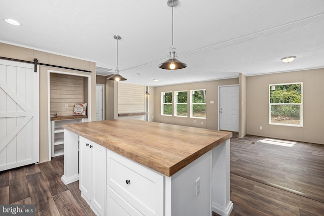 kitchen with wood counters, white cabinetry, hanging light fixtures, plenty of natural light, and a barn door