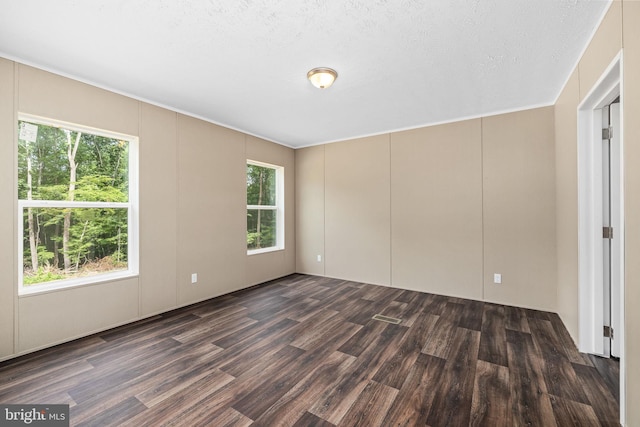 unfurnished room featuring dark wood-type flooring and a textured ceiling