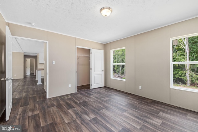 unfurnished bedroom featuring multiple windows, dark wood-type flooring, and a textured ceiling