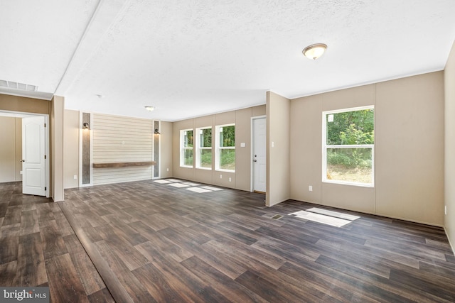 unfurnished living room featuring dark wood-type flooring and a textured ceiling