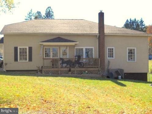 rear view of property with a wooden deck and a lawn