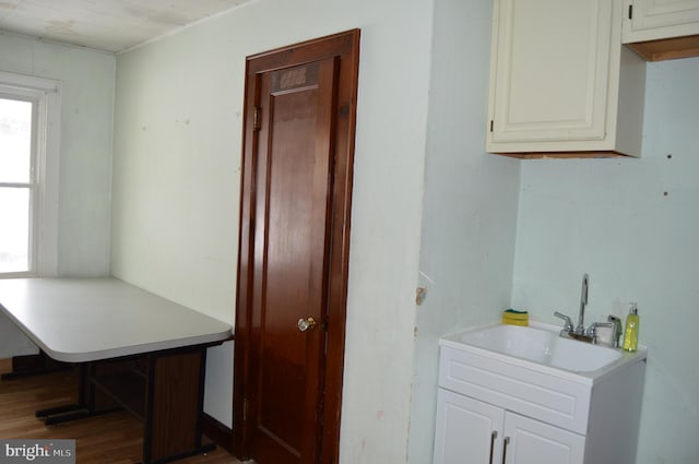 kitchen featuring sink, wood-type flooring, and white cabinets