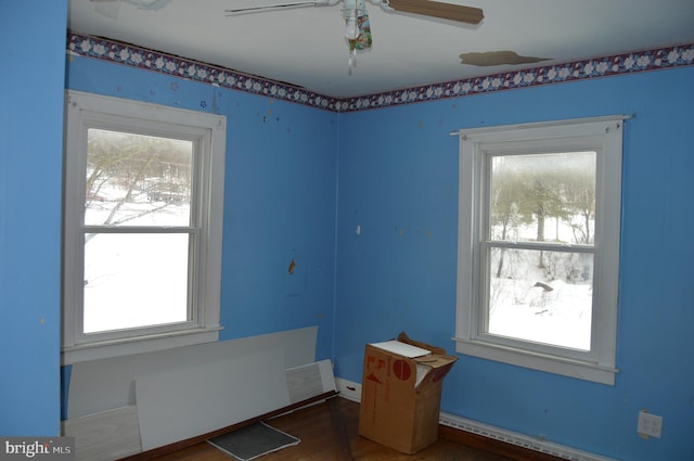 empty room with a baseboard heating unit, plenty of natural light, and ceiling fan