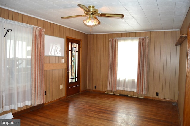 foyer entrance with dark wood-type flooring, wooden walls, and ceiling fan