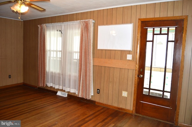 interior space with wooden walls, ceiling fan, and dark hardwood / wood-style flooring