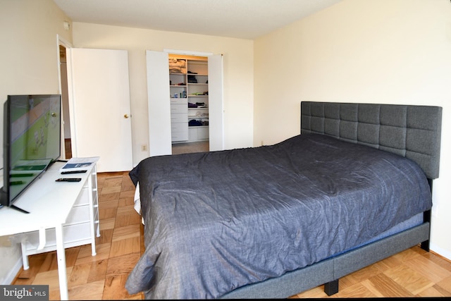 bedroom featuring a spacious closet and parquet floors